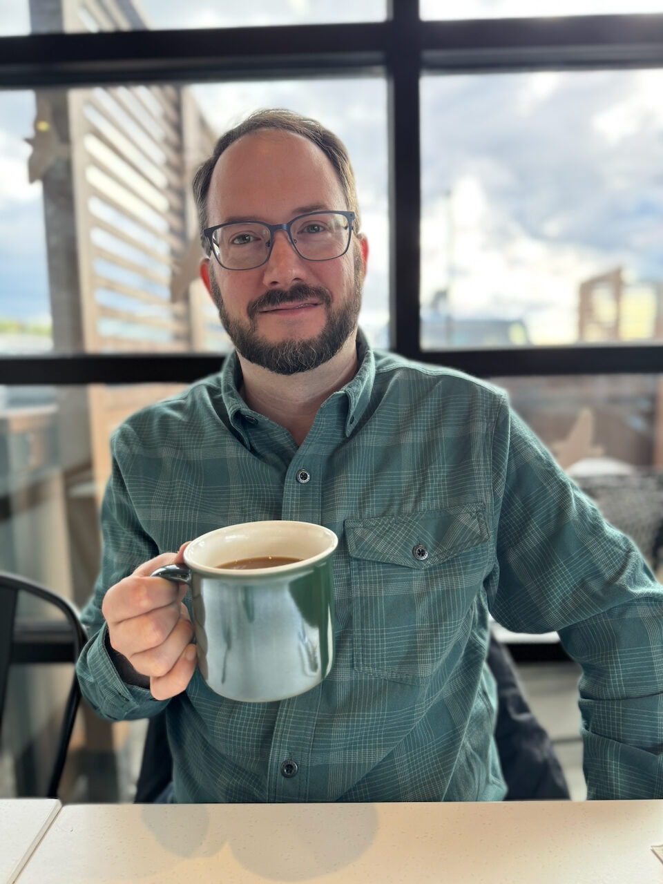 Calvin Freitas seated at a café in North Idaho, holding a coffee mug