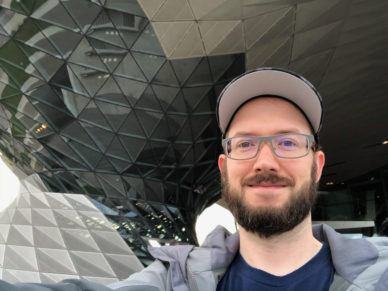 Calvin Freitas in front of the geometric glass façade of BMW Welt in Munich